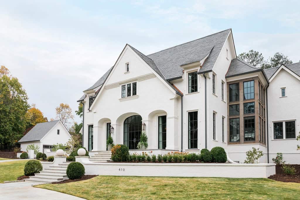 Modern English country house front exterior with white painted brick, steep gabled roofline and steel-framed windows in Georgia