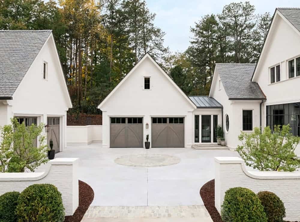 Modern English country house motor court with white stucco garages, wood carriage doors and circular driveway detail in Georgia