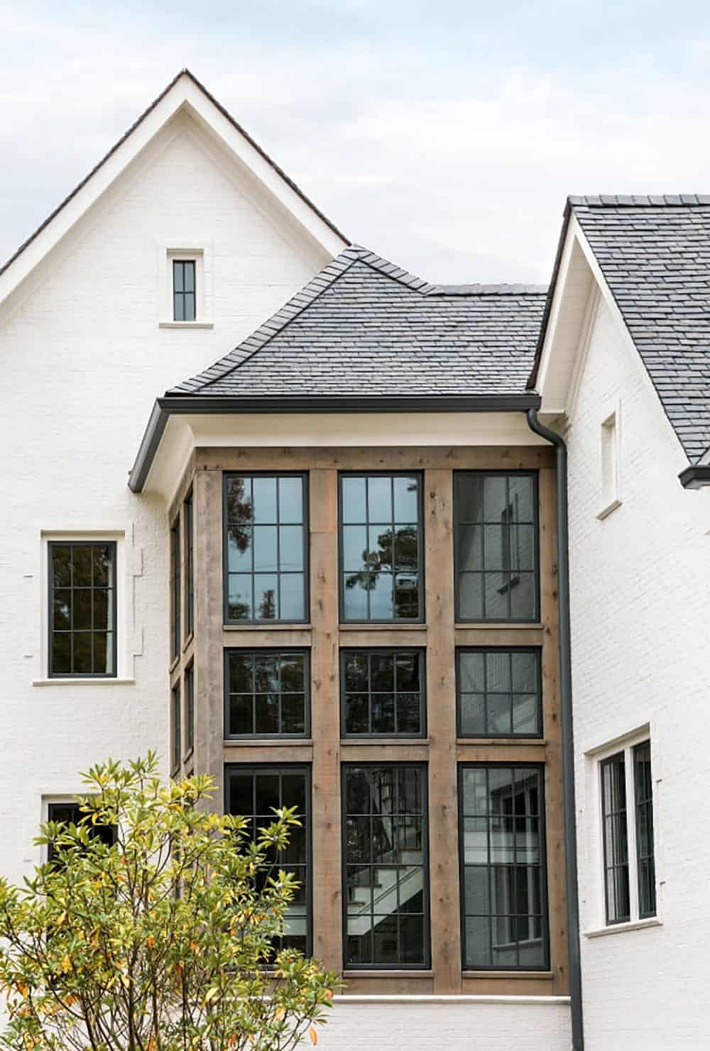 Modern English country house exterior stairwell with floor-to-ceiling cedar-framed steel window wall in Georgia