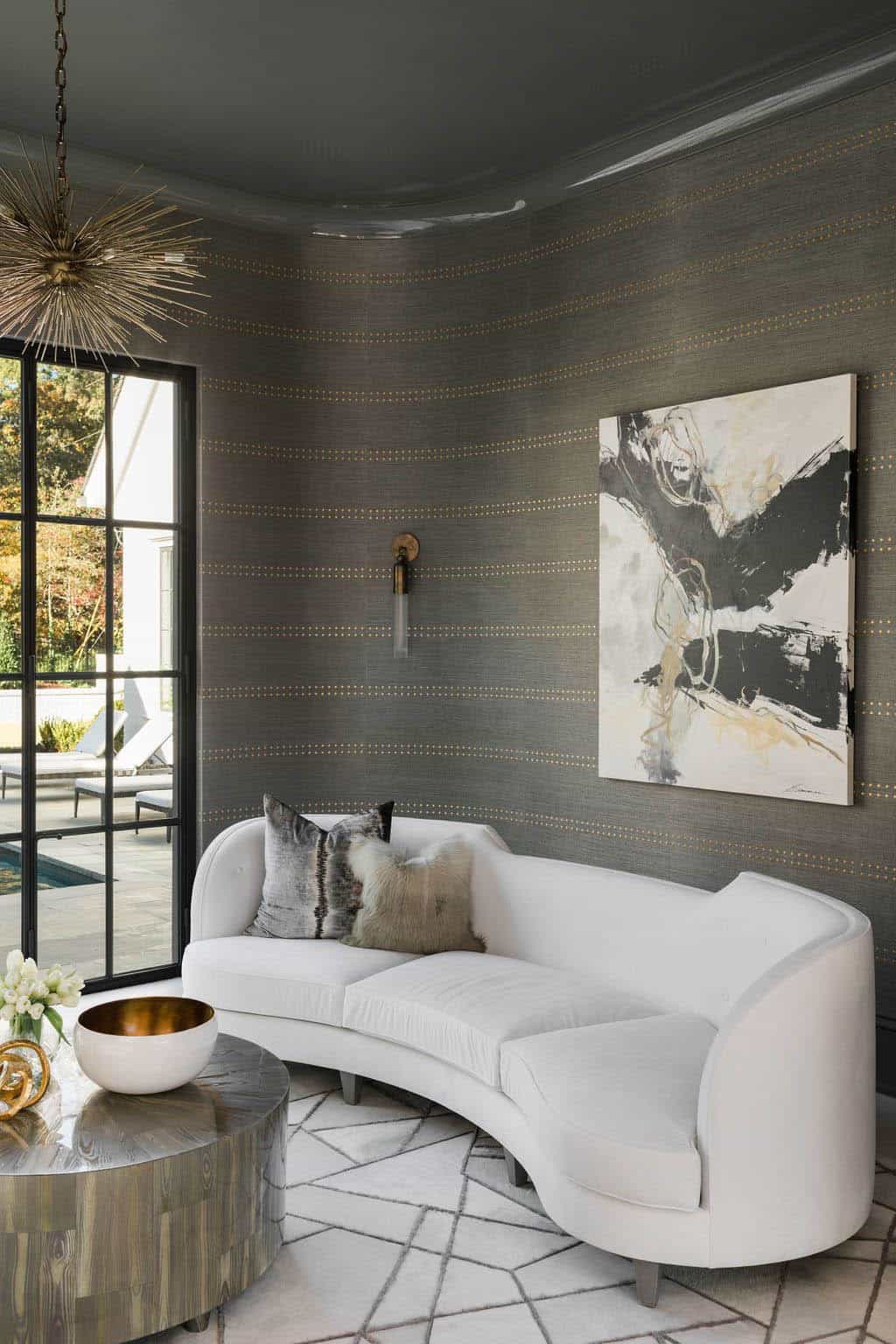 Modern English country living room with curved white sofa, grasscloth walls, Sputnik chandelier and steel-framed window in Georgia