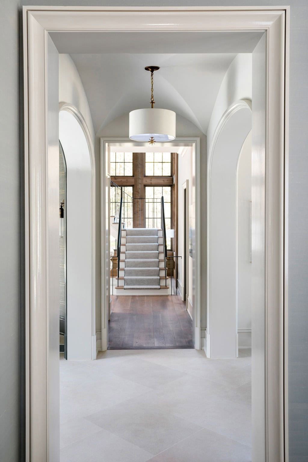Modern English country house hallway with arched doorways, barrel vaulted ceiling and staircase with cedar window wall in Georgia
