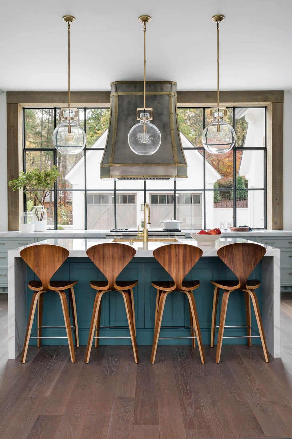 Modern English country kitchen with teal island, Cherner bar stools, custom zinc range hood and steel-framed window wall in Georgia
