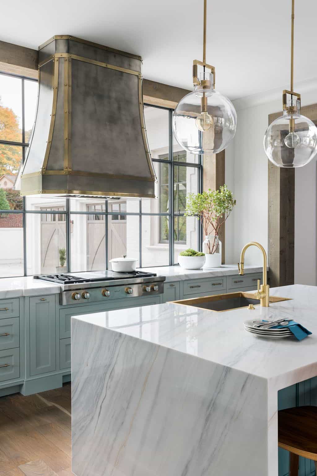 Modern English country kitchen with sage green cabinetry, marble waterfall island, custom zinc range hood and brass faucet in Georgia