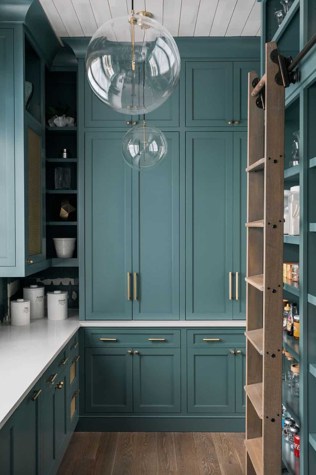 Modern English country butler's pantry with floor-to-ceiling teal cabinetry, brass hardware, rolling library ladder and globe pendant lights in Georgia