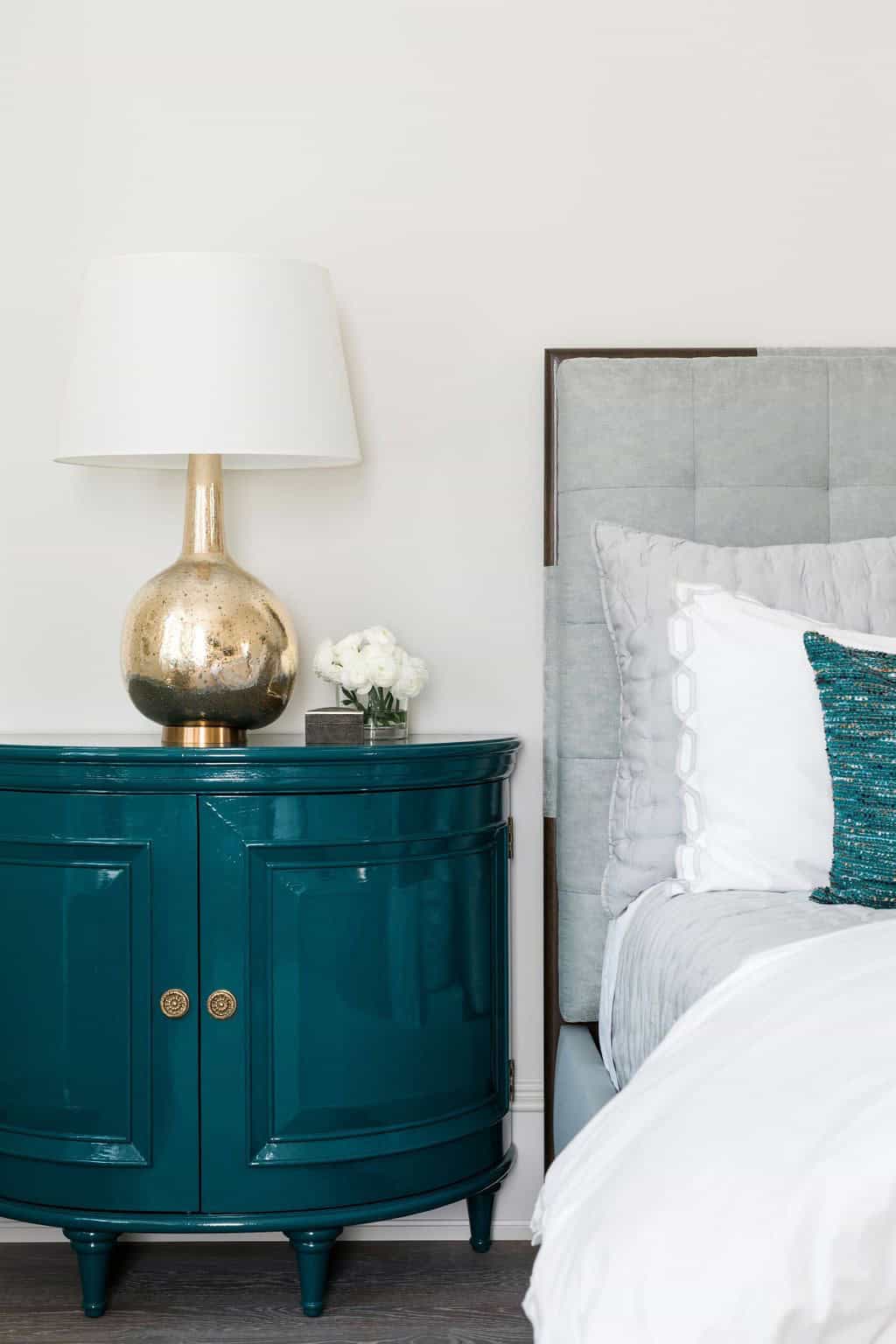 Modern English country primary bedroom teal lacquer demilune nightstand with brass lamp and upholstered headboard detail in Georgia