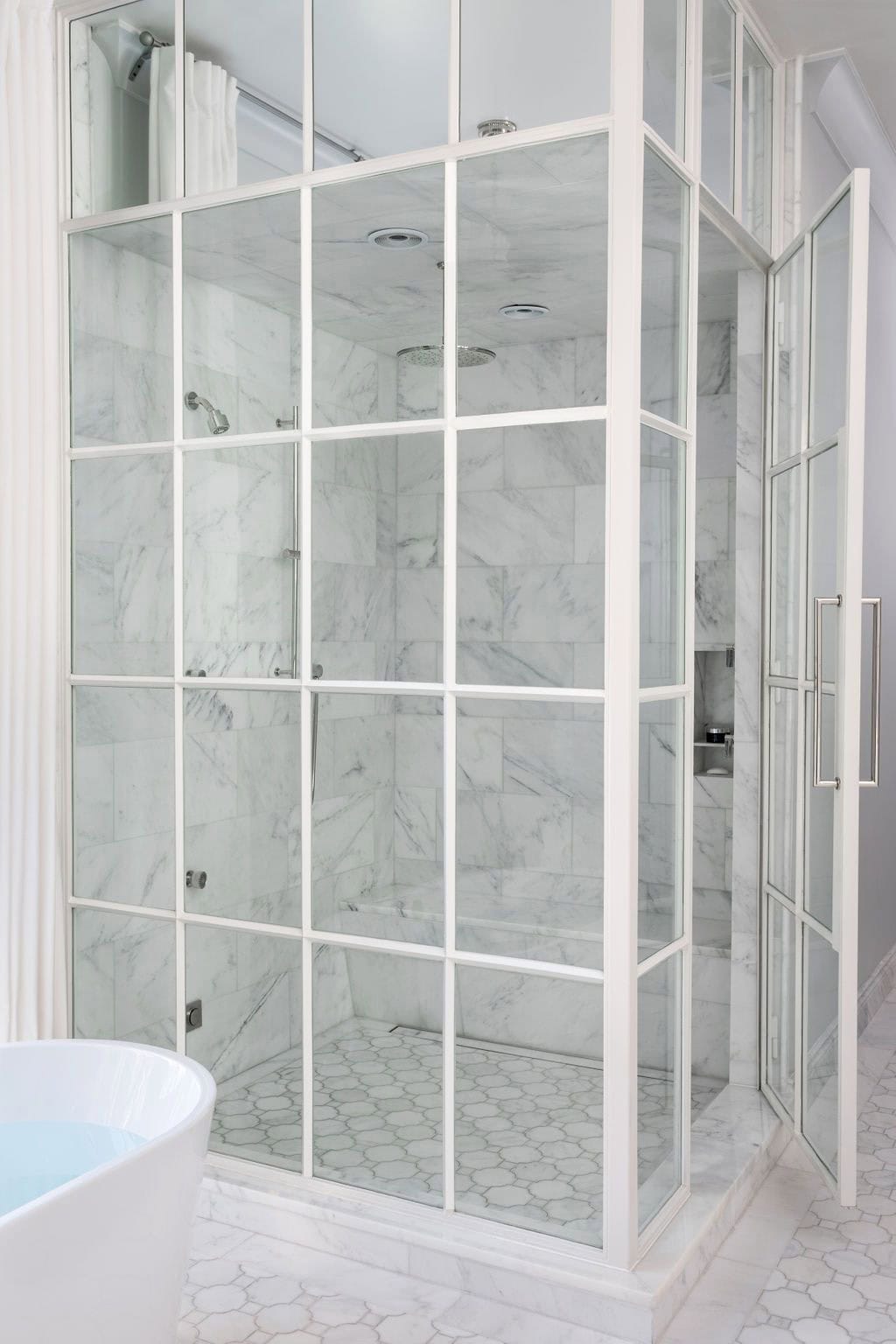 Modern English country primary bathroom with steel-framed glass shower enclosure, marble tile walls and mosaic tile floor in Georgia