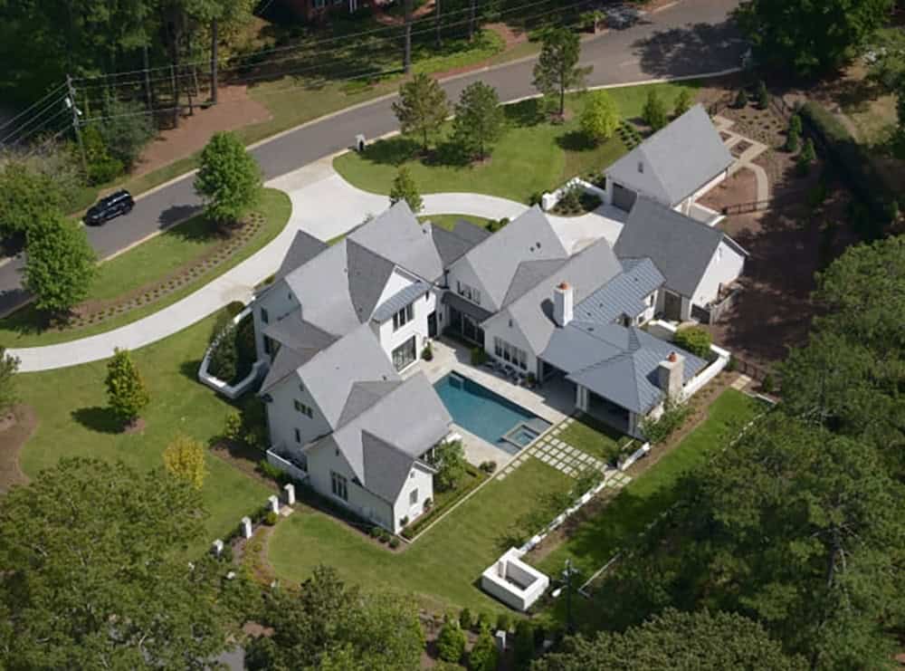 Aerial view of modern English country house with U-shaped plan, slate roof, pool and circular driveway in Georgia