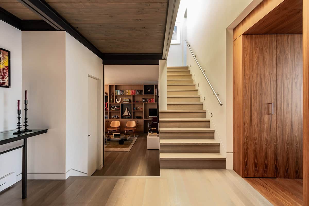 Floating home entryway with wood staircase, skylight, and built-in library
