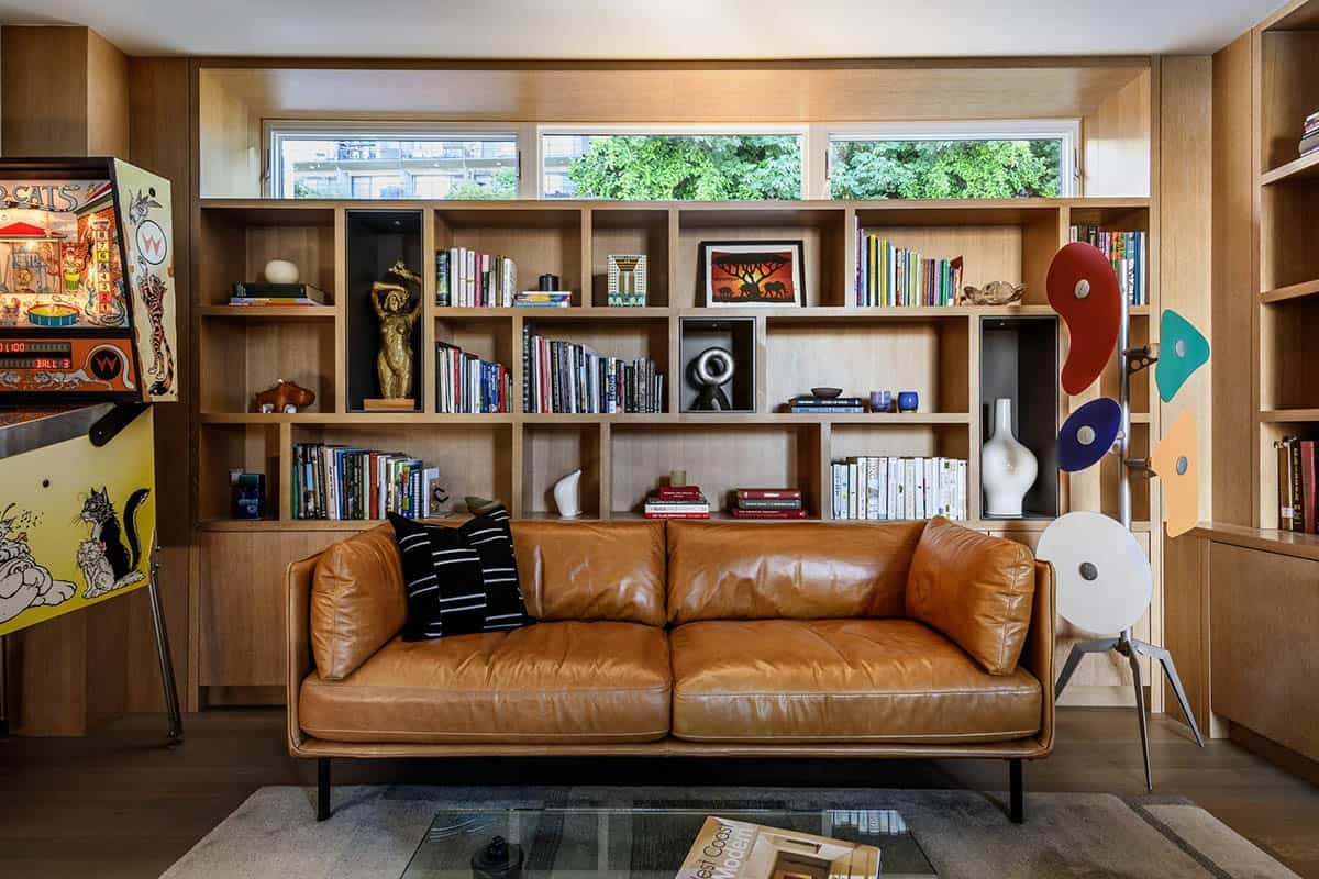 Leather sofa and built-in shelving in floating home den with pinball machine