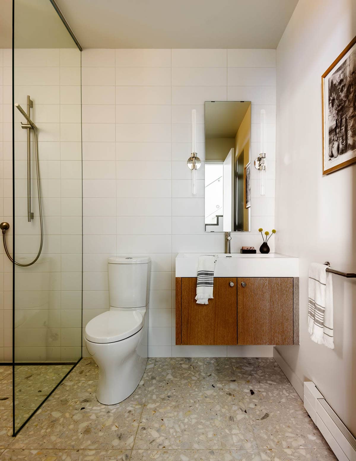 Modern bathroom with terrazzo floor, floating wood vanity, and glass shower
