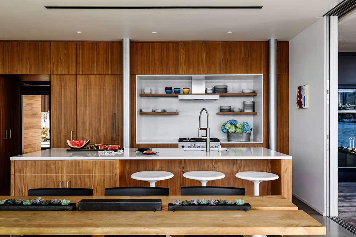 Modern kitchen with walnut cabinetry, white island, and open shelving