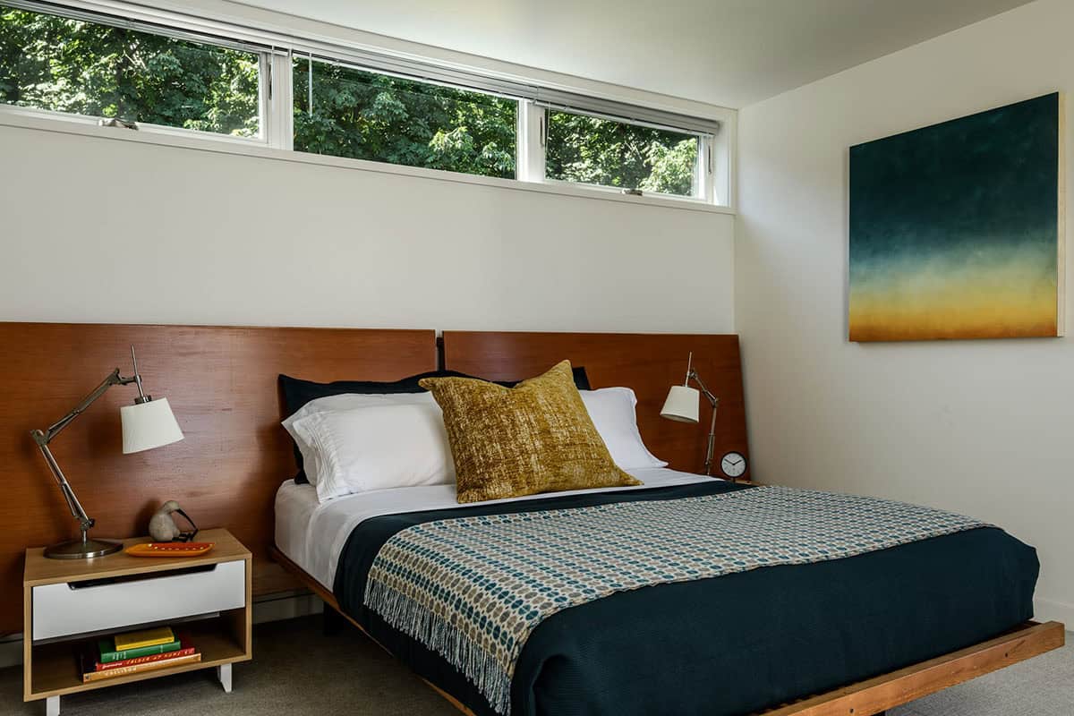Bedroom with wood headboard, clerestory window, and abstract painting