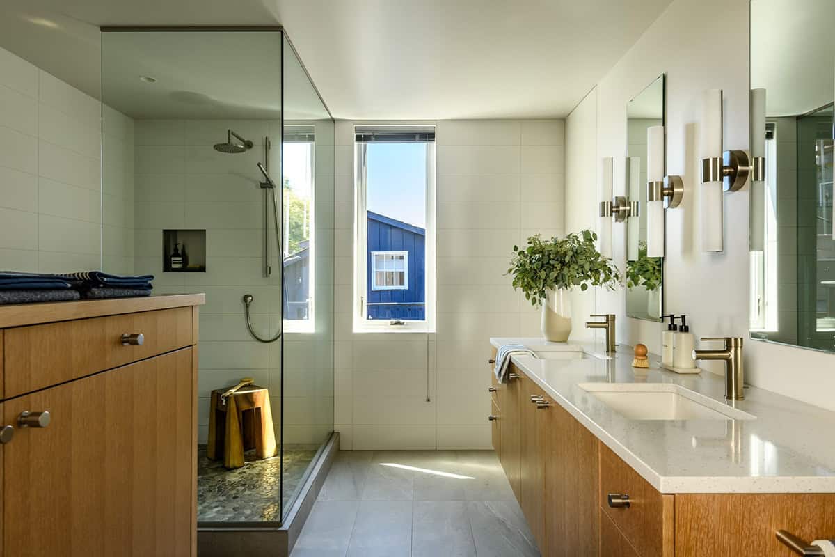 Primary bathroom with double vanity, brass fixtures, and glass shower