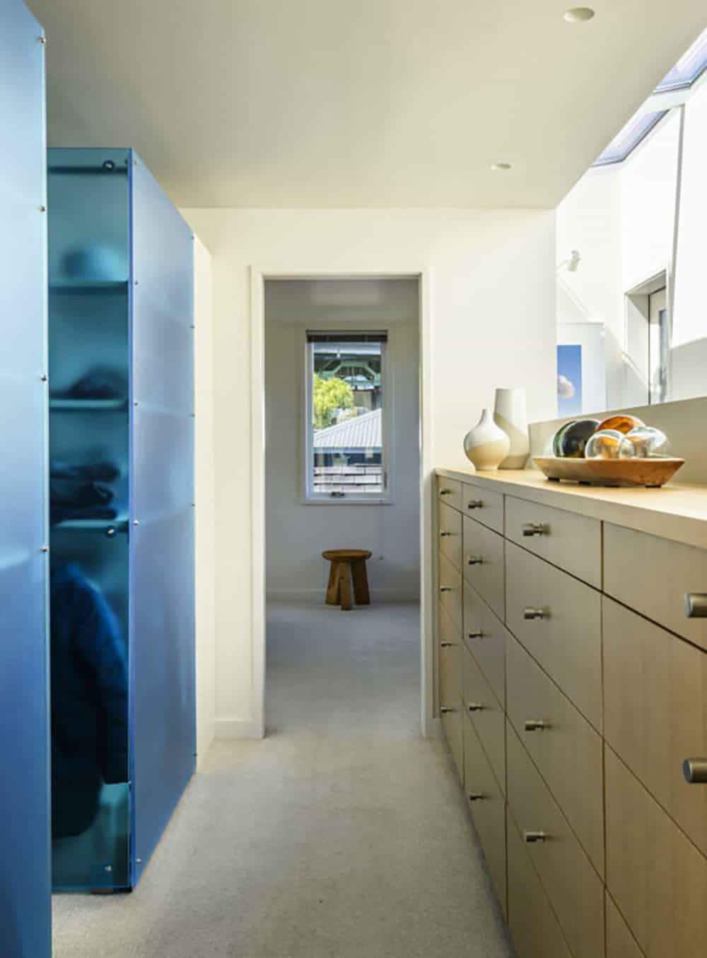 Walk-in closet with blue glass wardrobe doors and built-in oak drawers in Seattle floating home