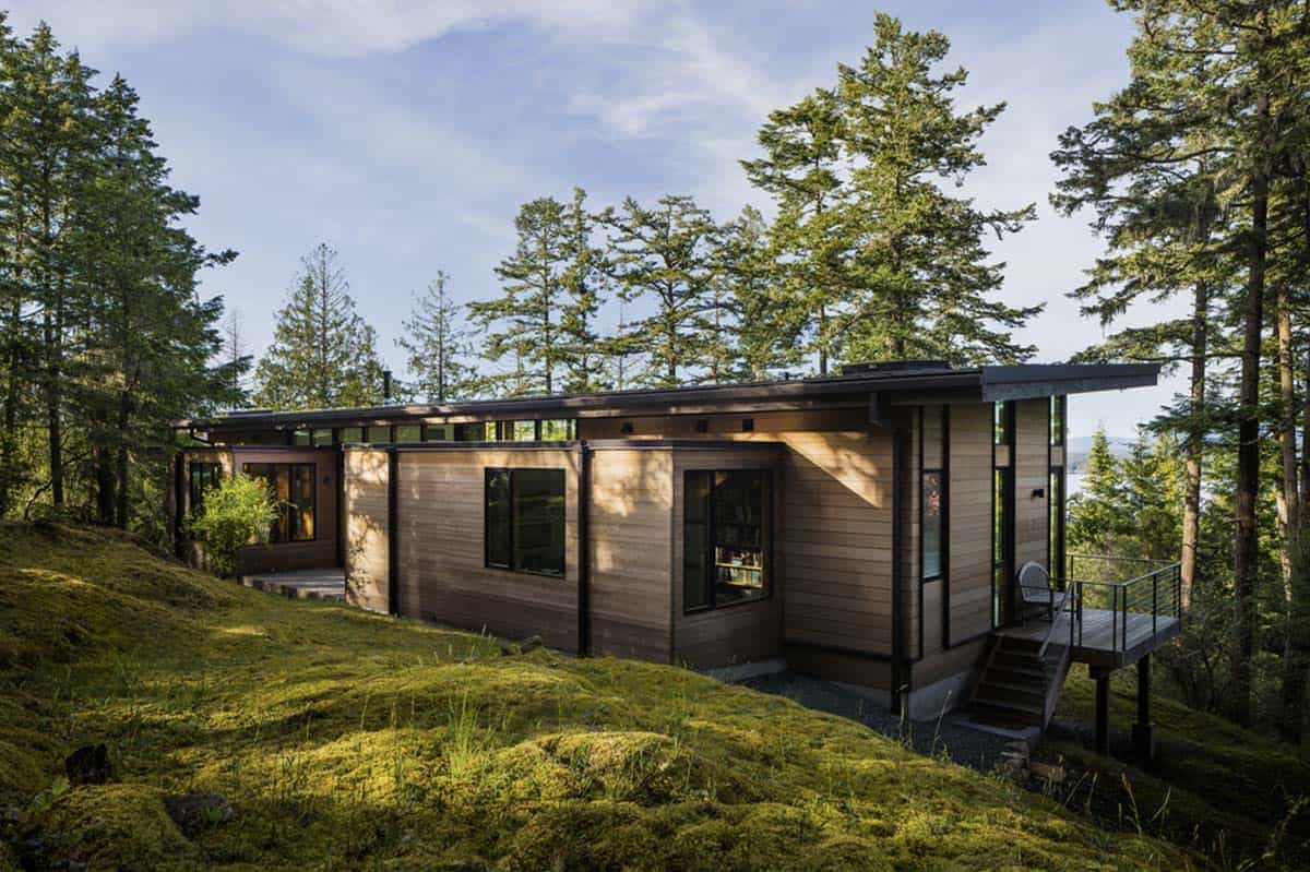 Side view of cedar home with clerestory windows, metal deck stairs, and water views through trees