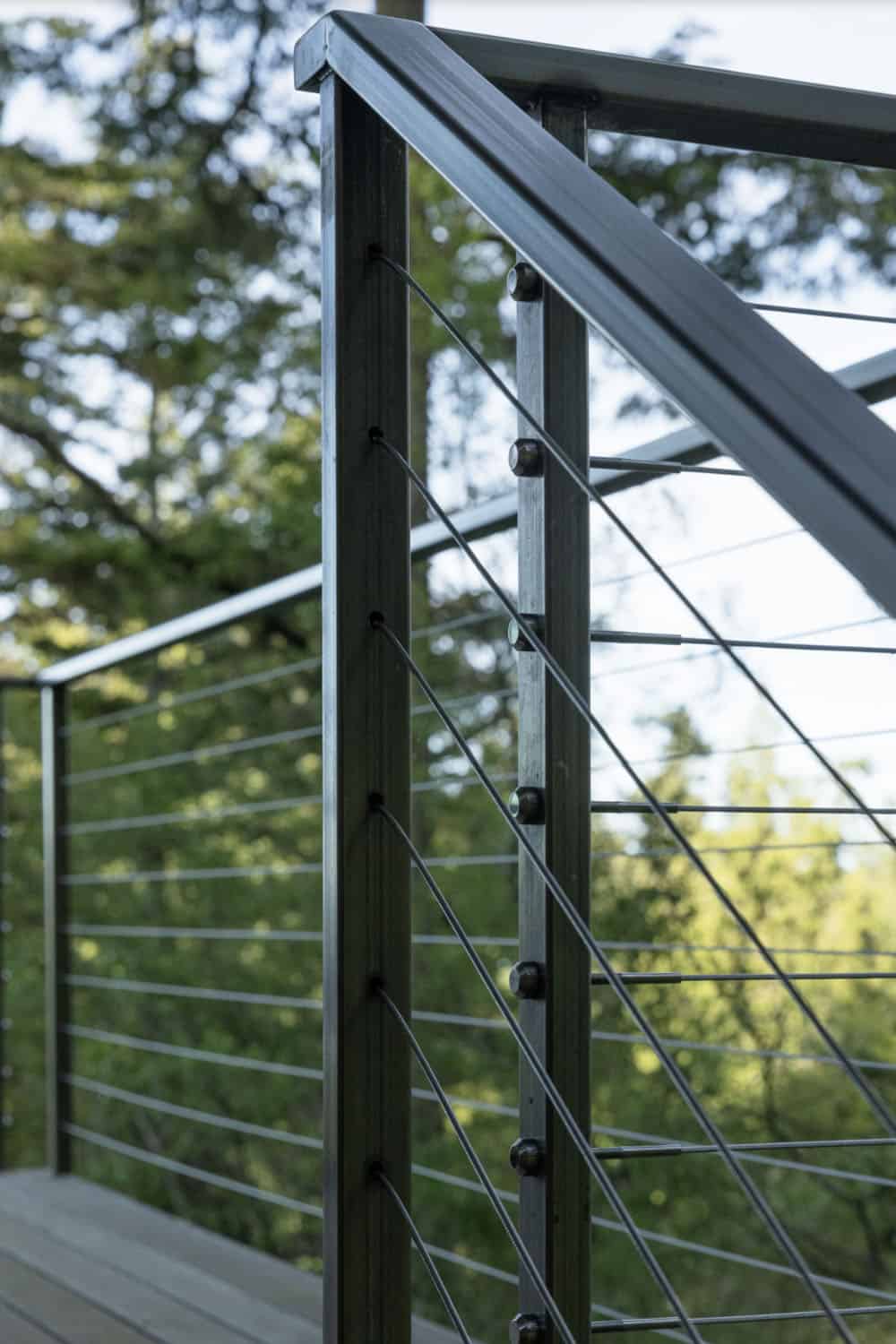 Close-up detail of stainless steel cable railing with wood posts at corner of elevated deck