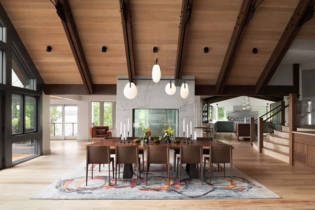 Formal dining room with dark wood table, vaulted ceiling, pendant lights, and double-sided marble fireplace