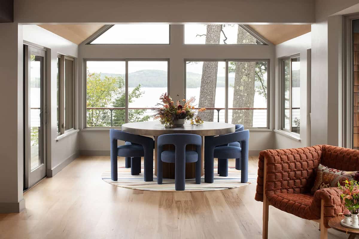 Breakfast nook with round table, sculptural navy chairs, and wraparound windows with lake view