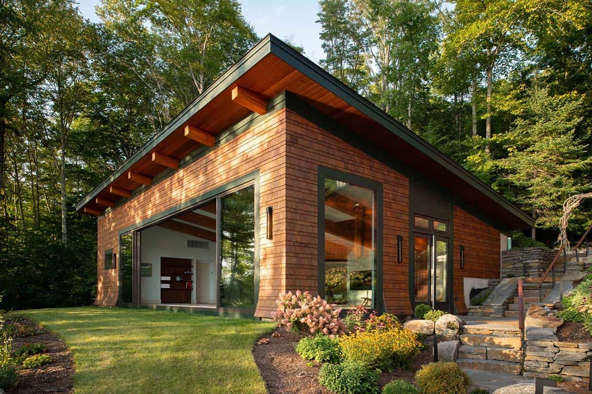 Modern cedar-clad pool house with flat roof, exposed beams, and floor-to-ceiling sliding glass doors