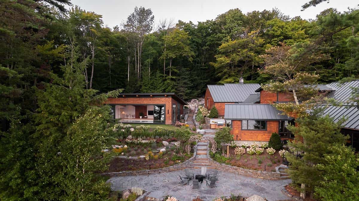 Aerial view of multi-structure lakehouse compound with pool house, stone pathways, and landscaped gardens