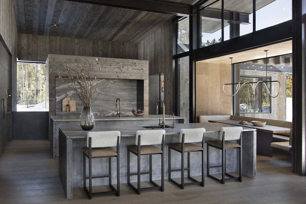 Kitchen island with fur-backed bar stools, swirling marble backsplash, and breakfast nook beyond