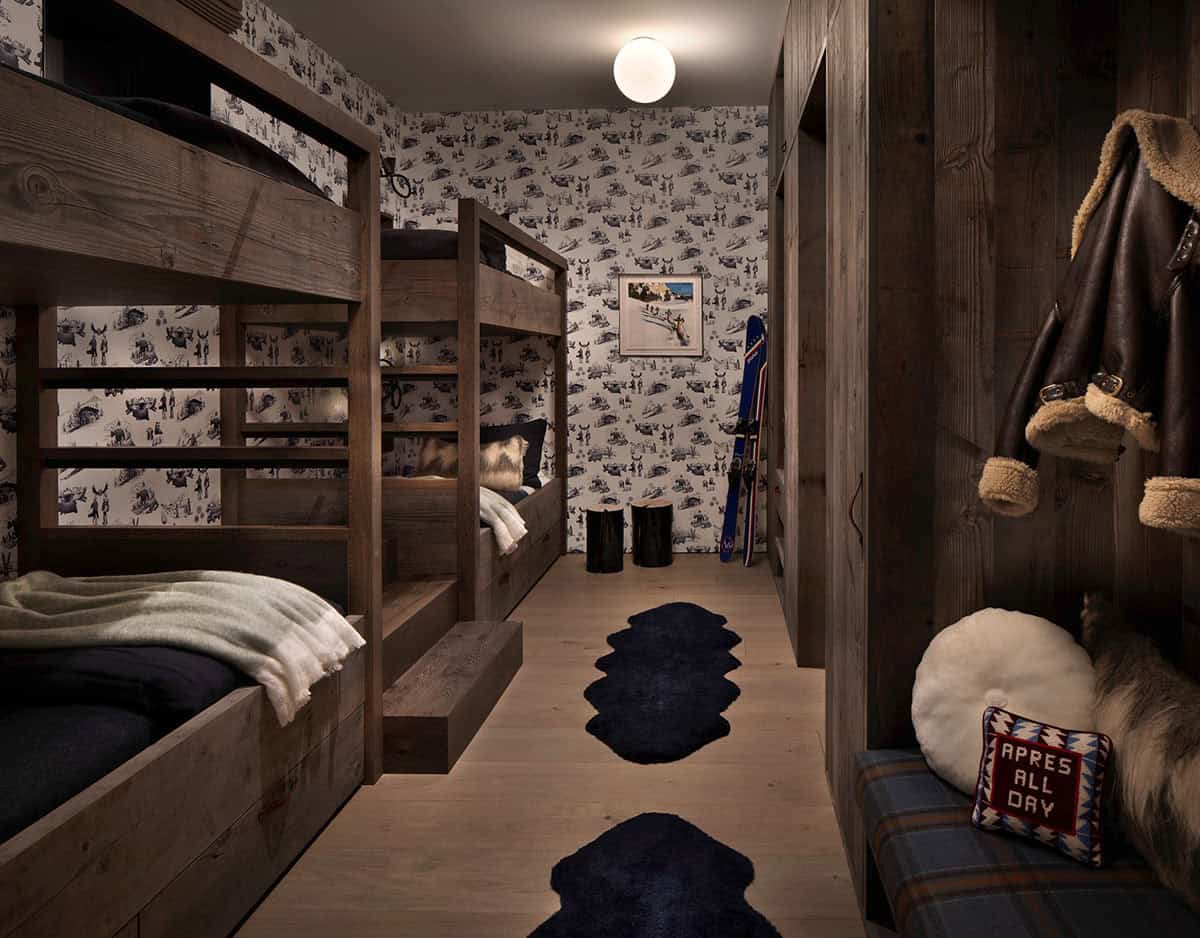 Ski chalet bunk room with reclaimed wood bunks, ski-themed toile wallpaper, and apres-ski accessories