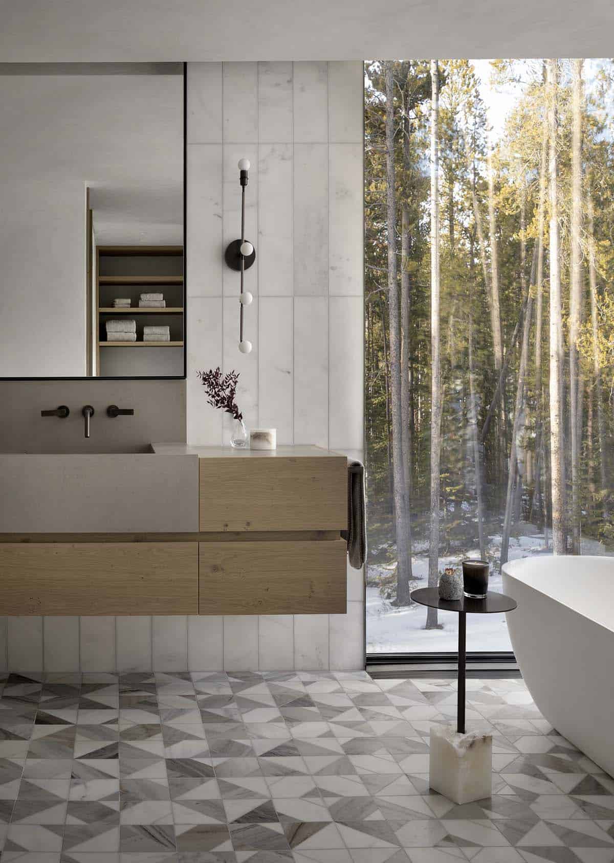 Bathroom with floating oak vanity, geometric marble floor tile, globe wall sconce, and floor-to-ceiling forest window