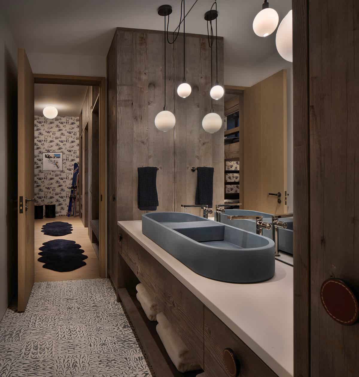 Bunk room bathroom with slate blue double vessel sink, globe pendants, reclaimed wood walls, and patterned floor tile