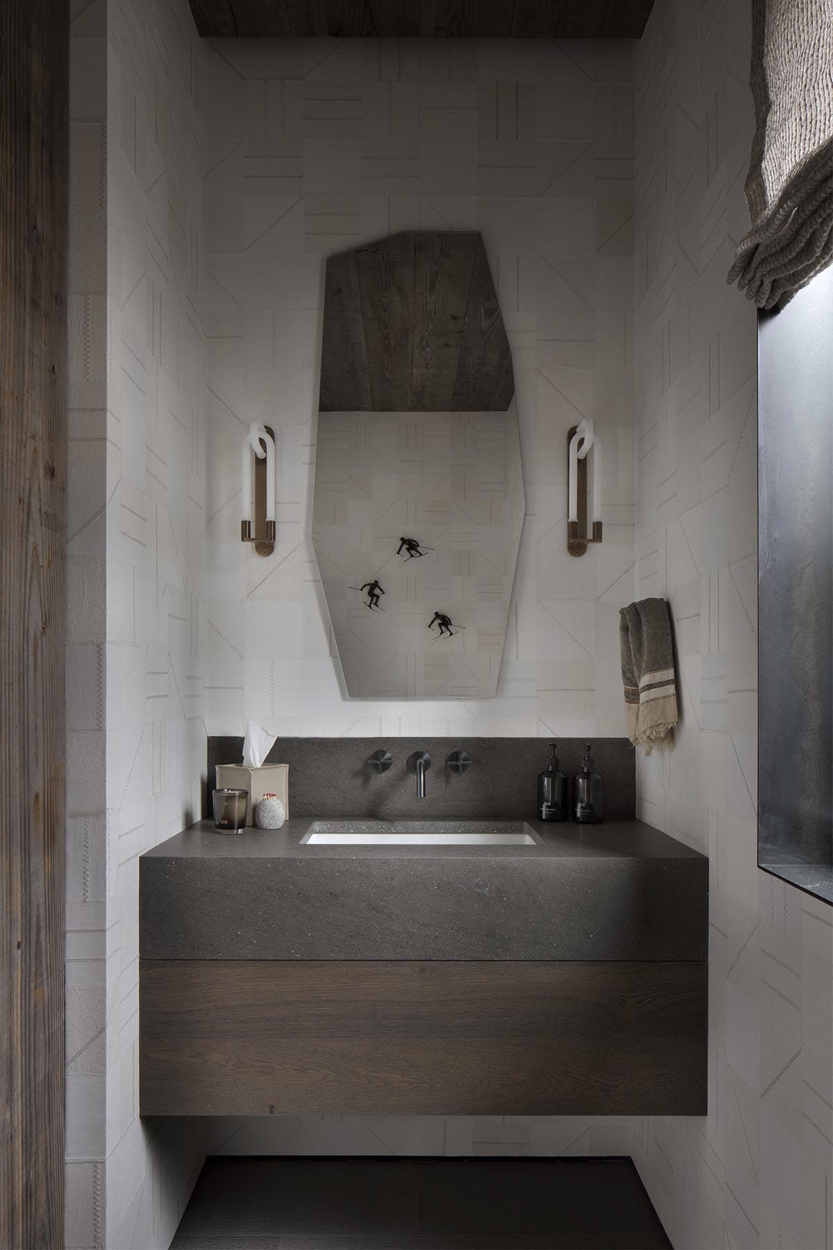 Powder room with geometric white tile, angled wood-framed mirror, skier artwork reflection, and concrete floating vanity