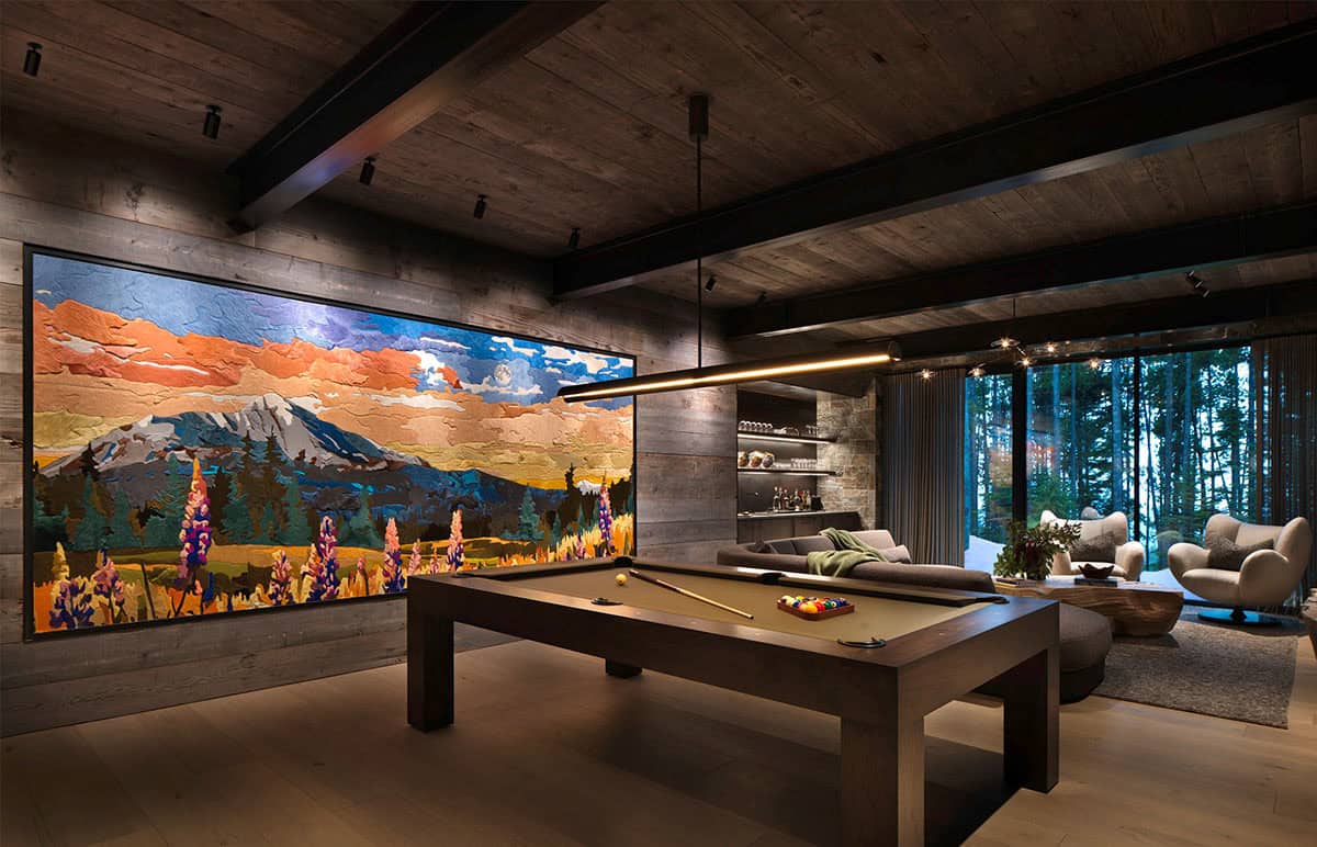 Pool table room with massive colorful Montana landscape wall art, linear pendant light, and forest views beyond