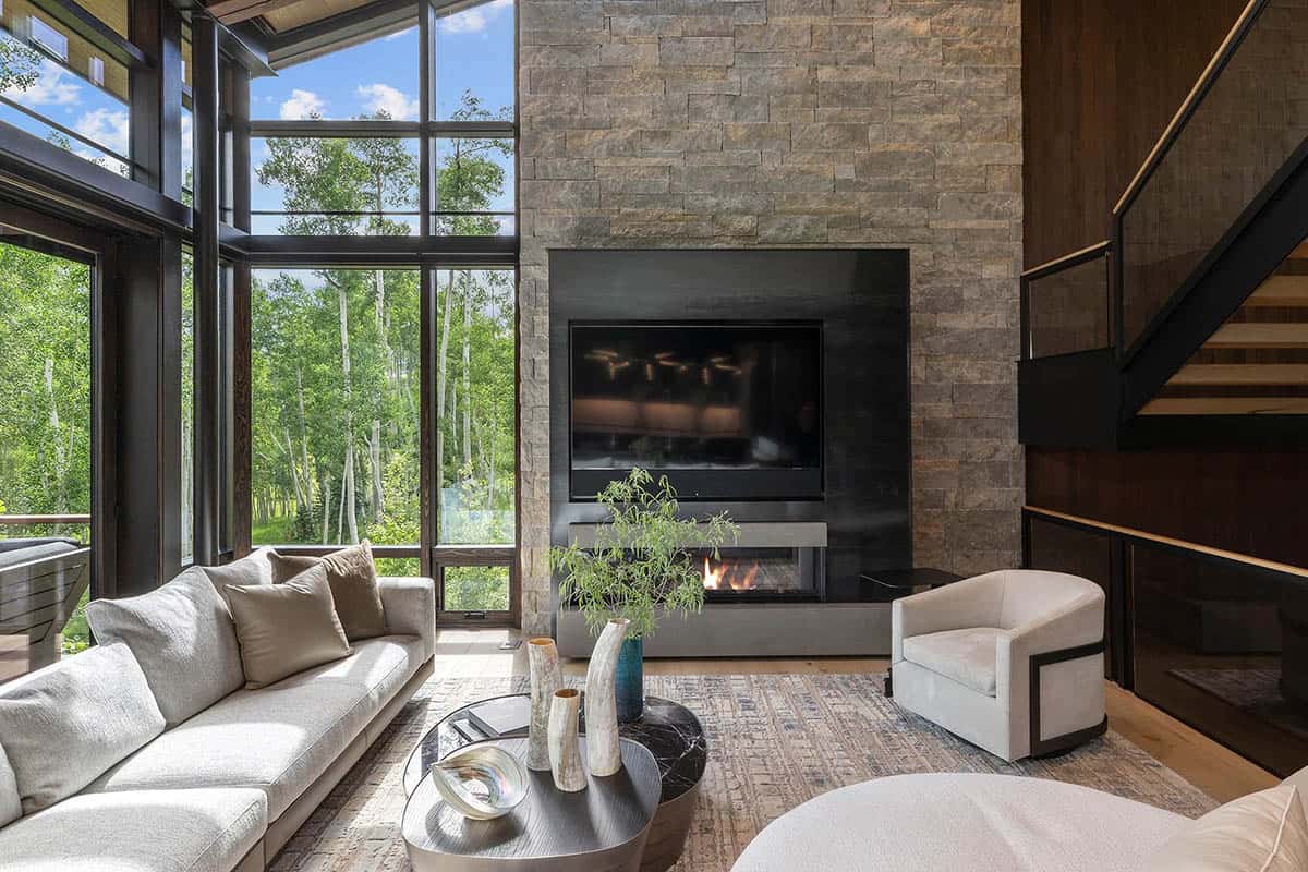Double-height living room with stacked stone fireplace, linear gas insert, and glass walls