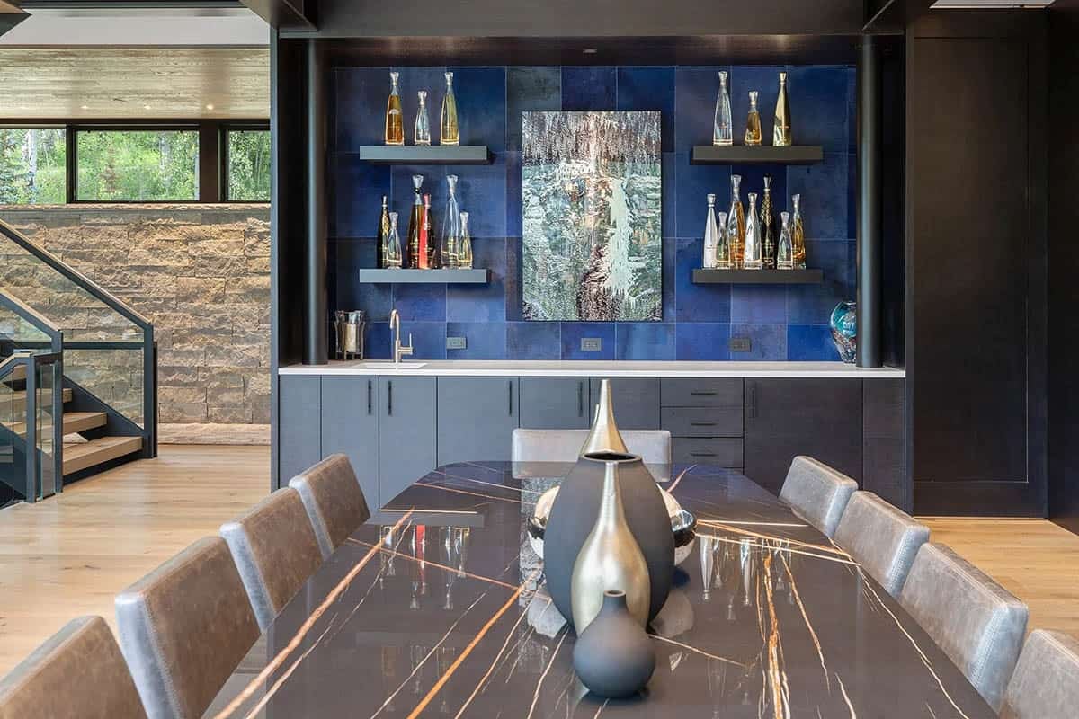 Formal dining room with black marble table, blue zellige tile bar wall, and floating shelves