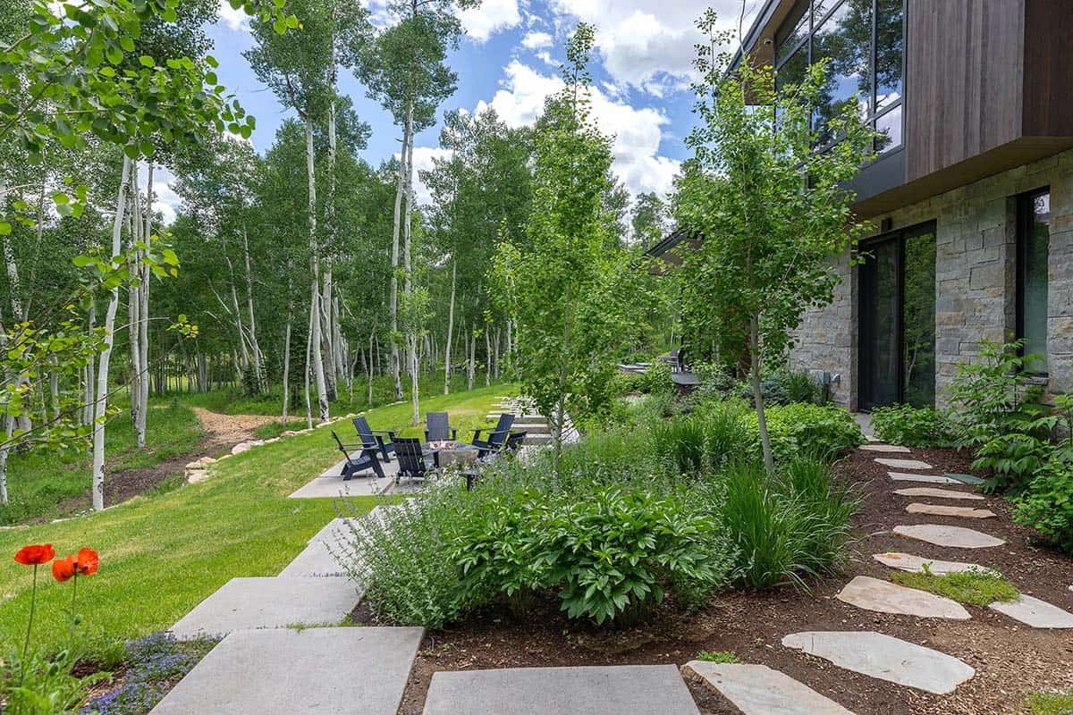 Landscaped yard with flagstone stepping path, wildflower plantings, fire pit seating, and aspen forest