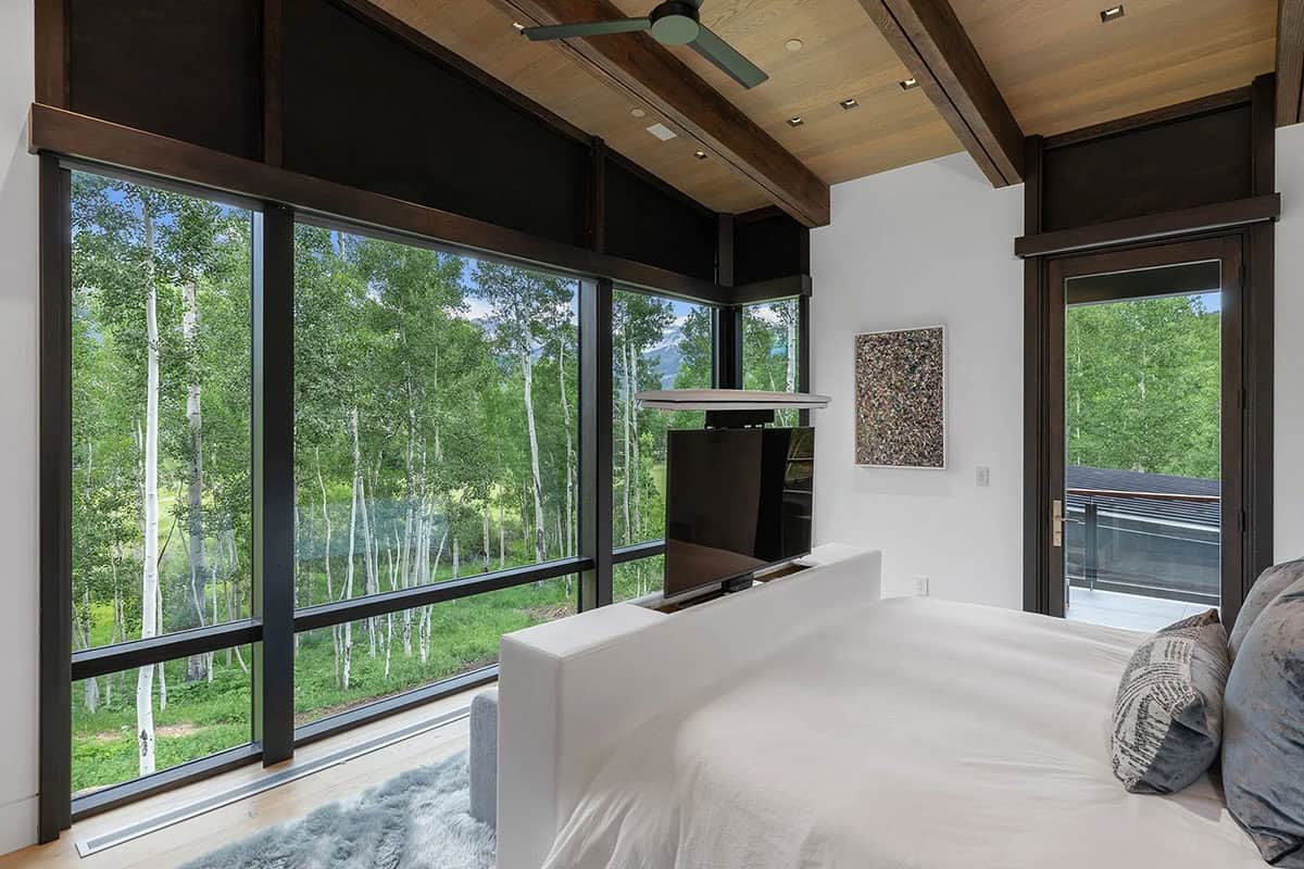 Primary bedroom with motorized blackout shades, pop-up TV cabinet, exposed beams, and panoramic aspen views