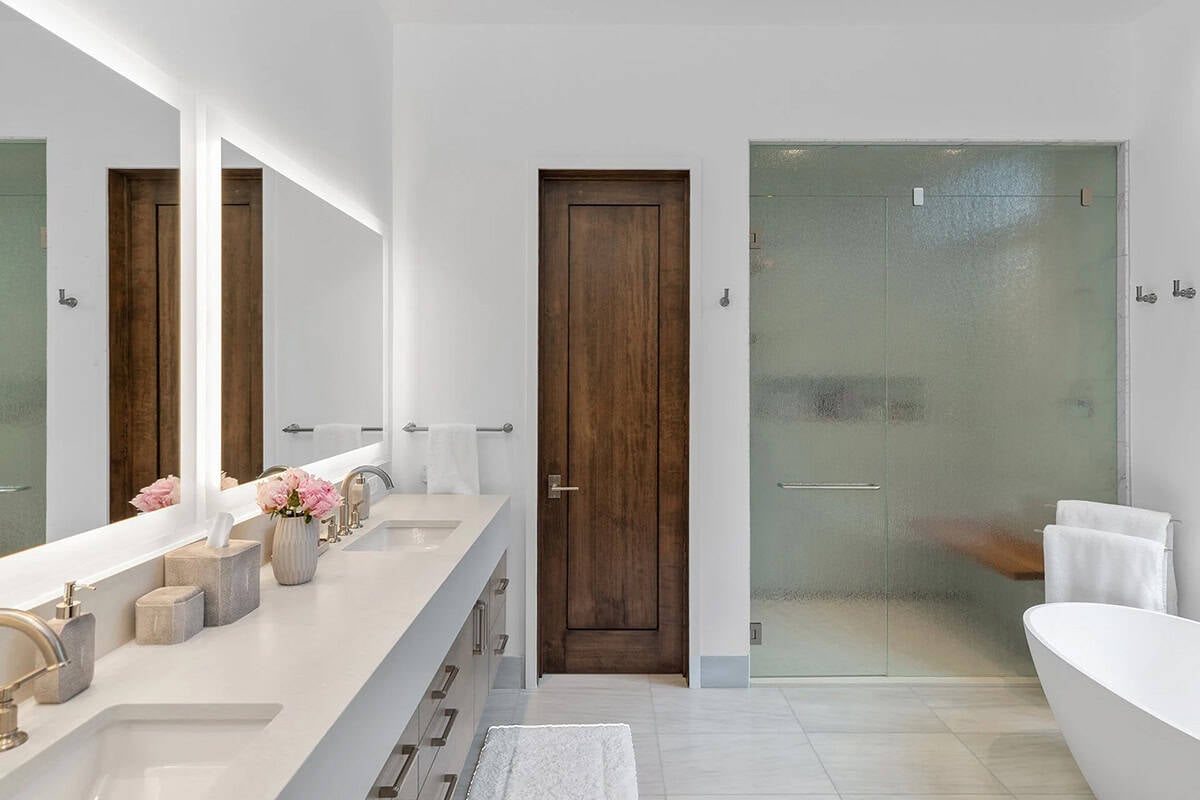 Primary bathroom with double vanity, backlit mirrors, glass steam shower, and freestanding soaking tub