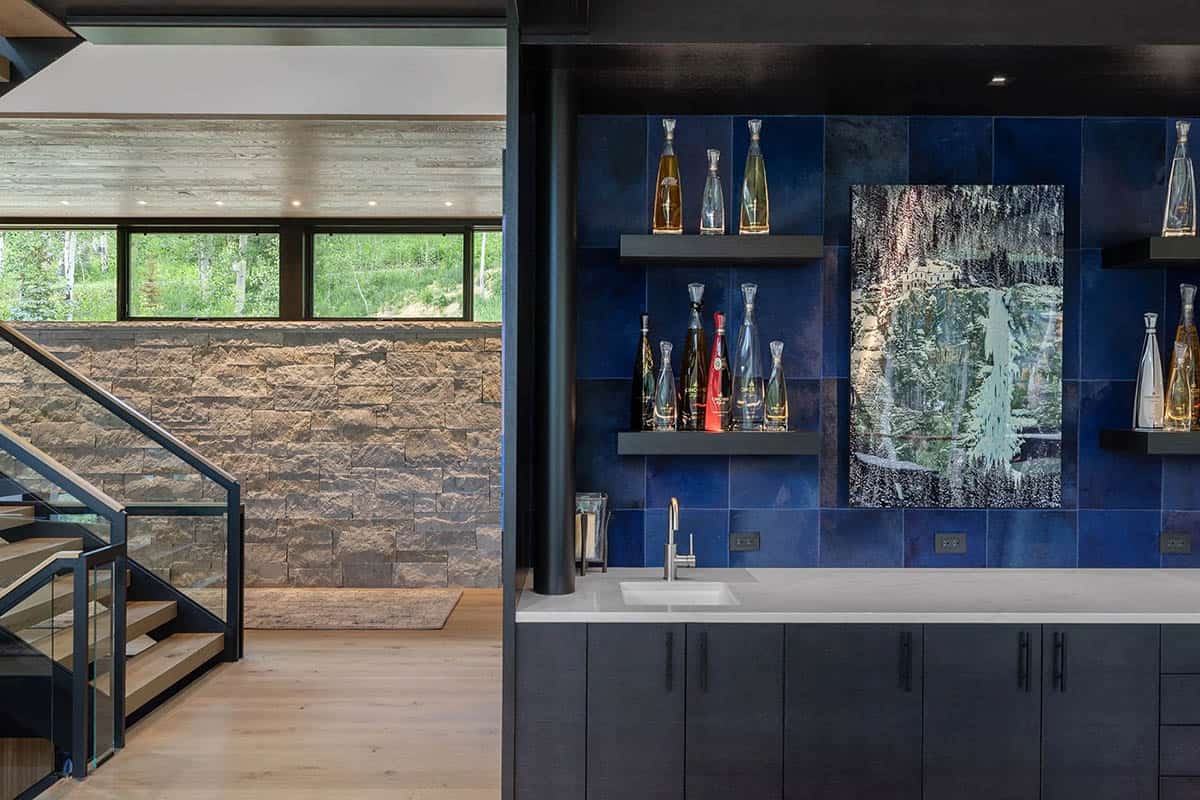 Wet bar with cobalt blue zellige tile backsplash, floating shelves, white quartz counter, and adjacent stone staircase wall