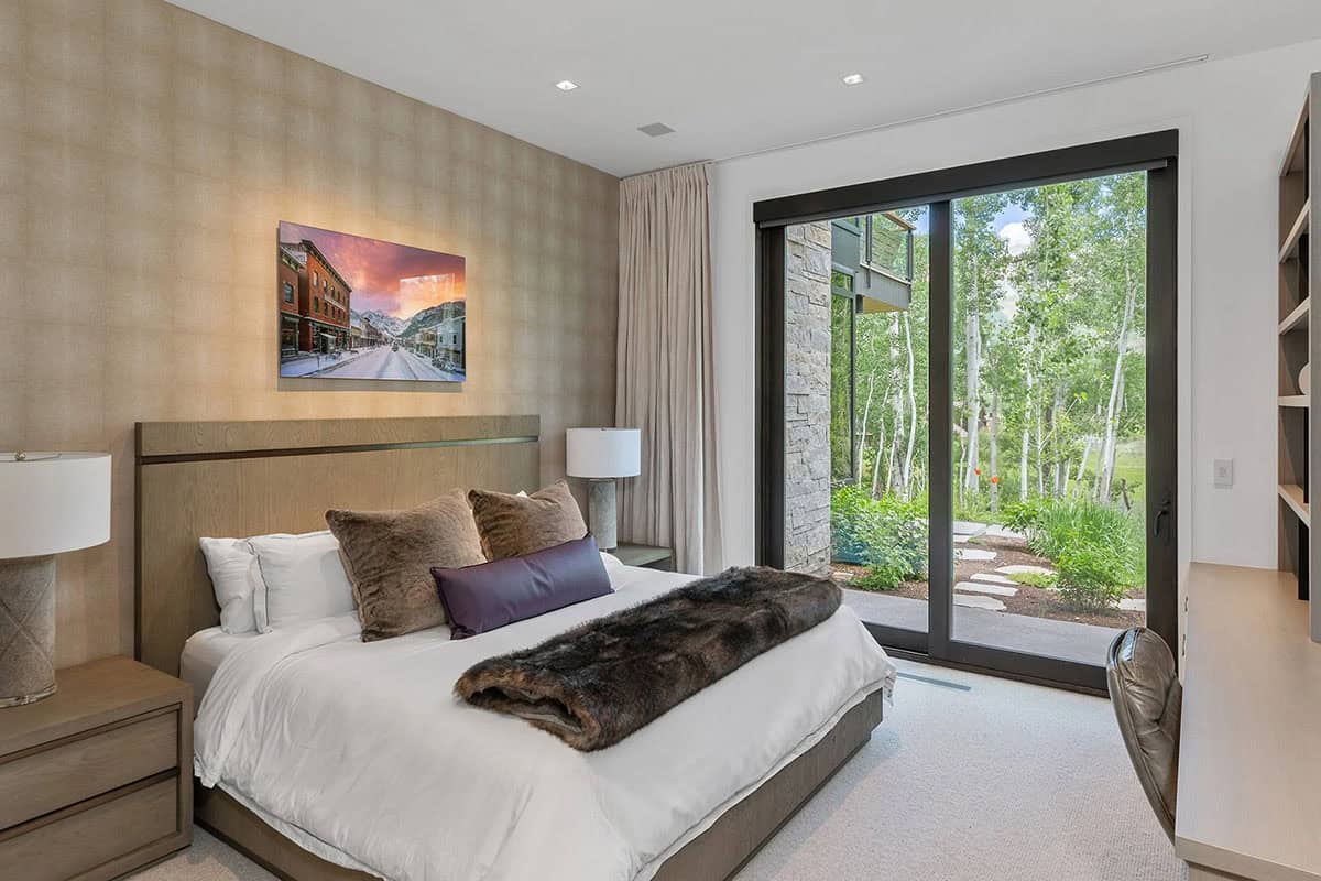 Guest bedroom with wood-paneled headboard wall, fur throw, sliding glass door, and Telluride street photography artwork