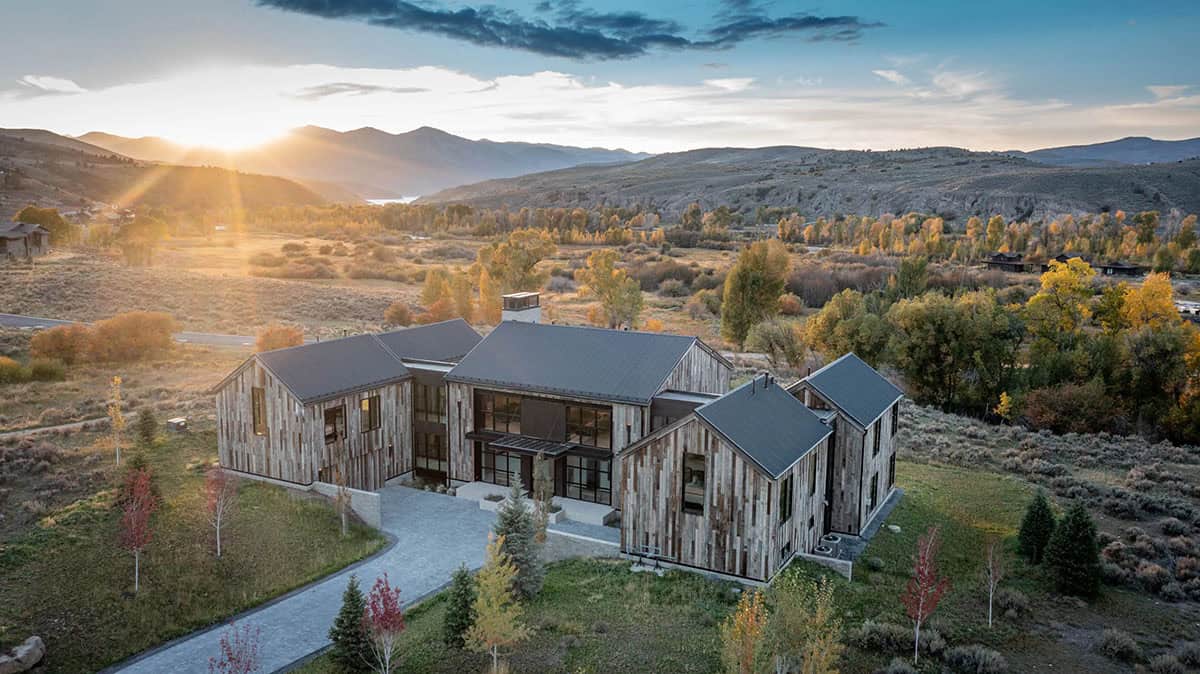 Aerial sunset view of reclaimed wood estate surrounded by fall foliage and Utah mountains