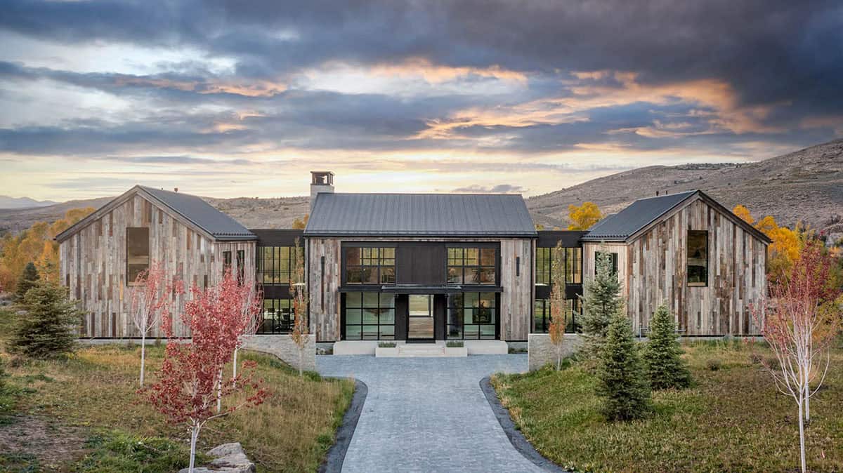 Front facade of reclaimed wood mountain home at dusk with cobblestone driveway