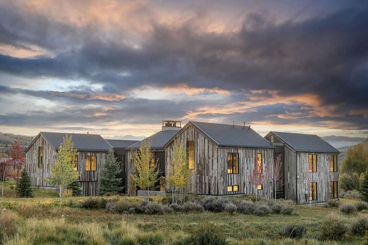 Reclaimed wood barn-style home glowing at sunset against dramatic stormy Utah sky
