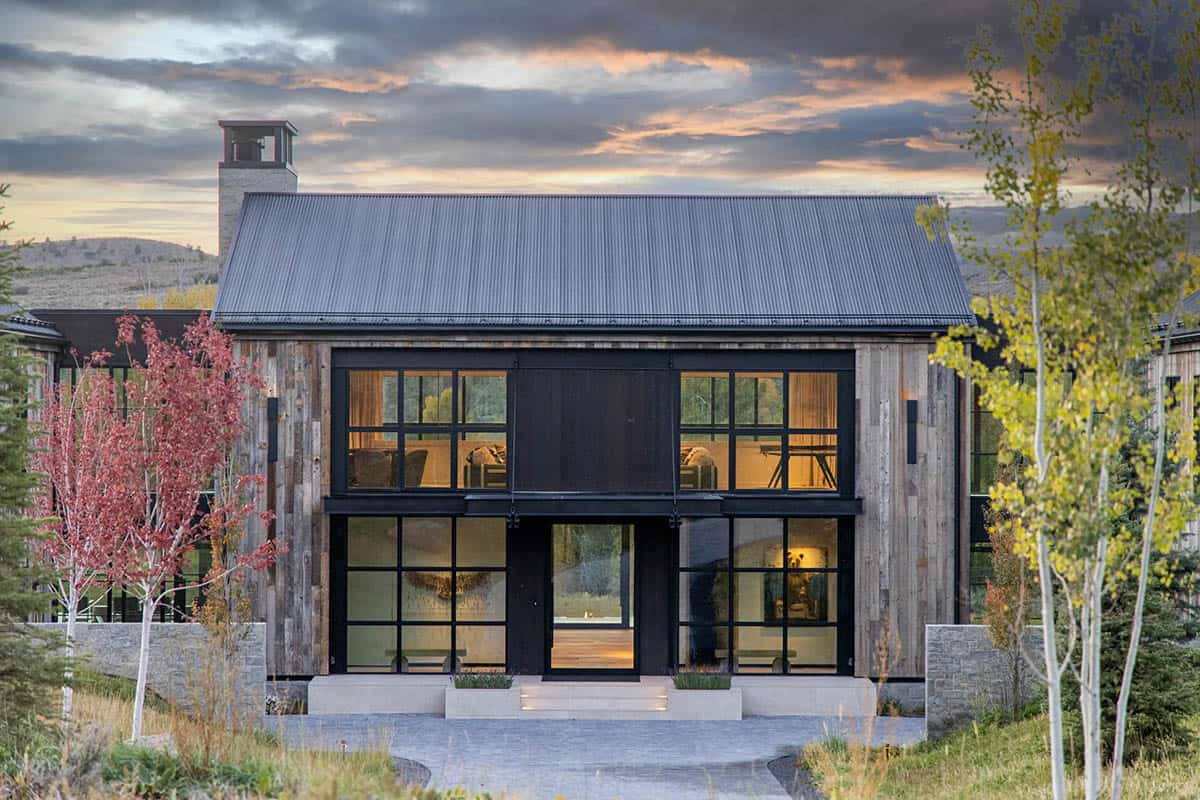 Entry facade of reclaimed wood home with large steel-framed sliding barn door at dusk