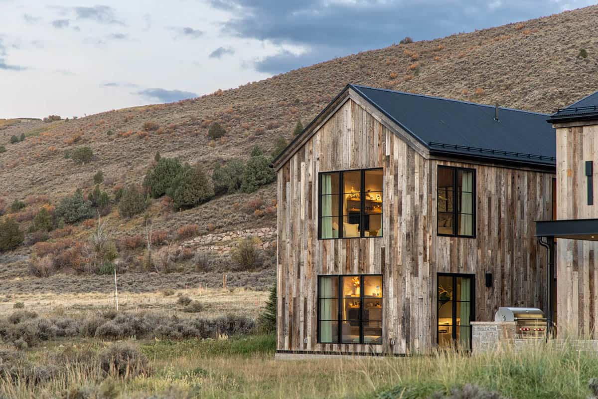 Reclaimed wood gable end with black steel windows against sage-covered Utah hillside