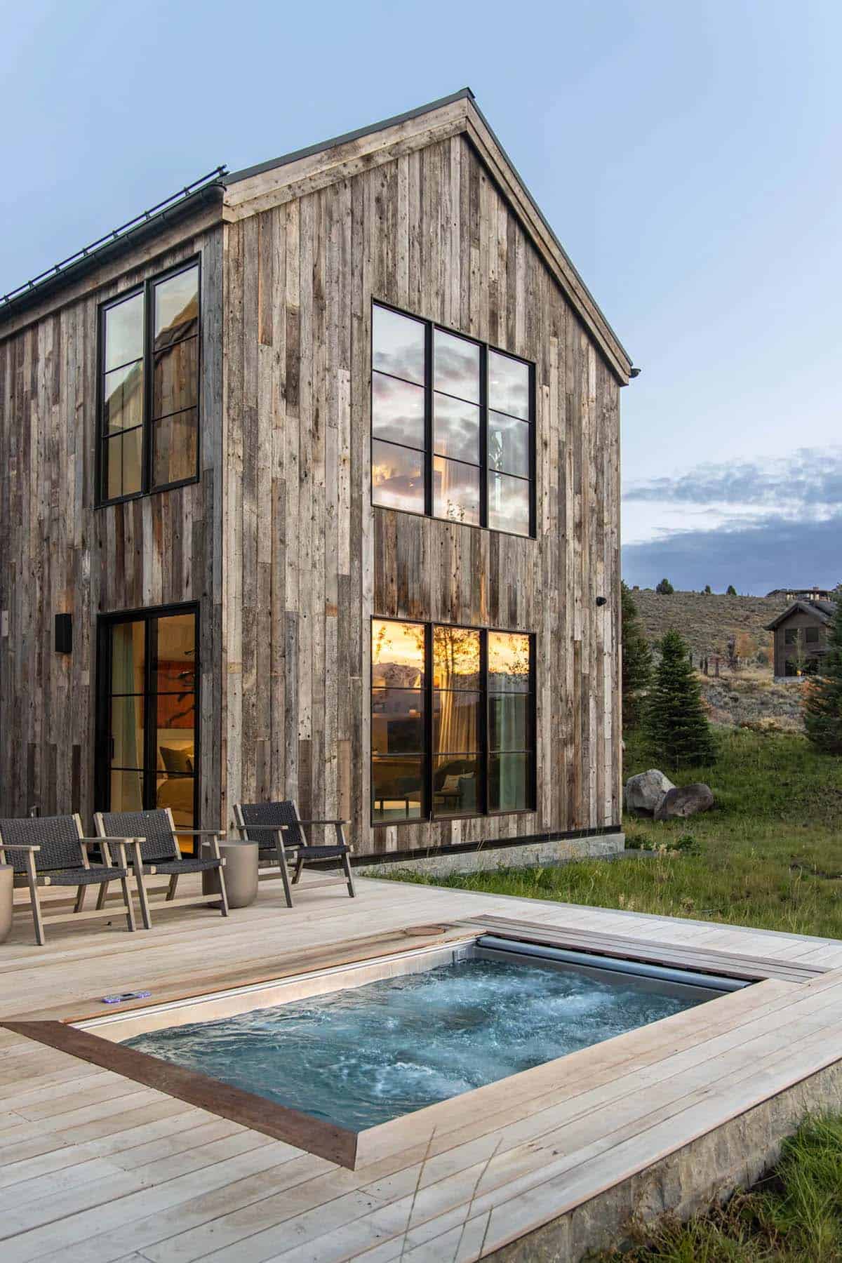 Flush-mount hot tub on wood deck beside reclaimed wood gable at sunset