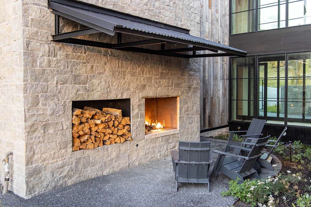 Outdoor stone fireplace with built-in firewood storage and Adirondack chairs