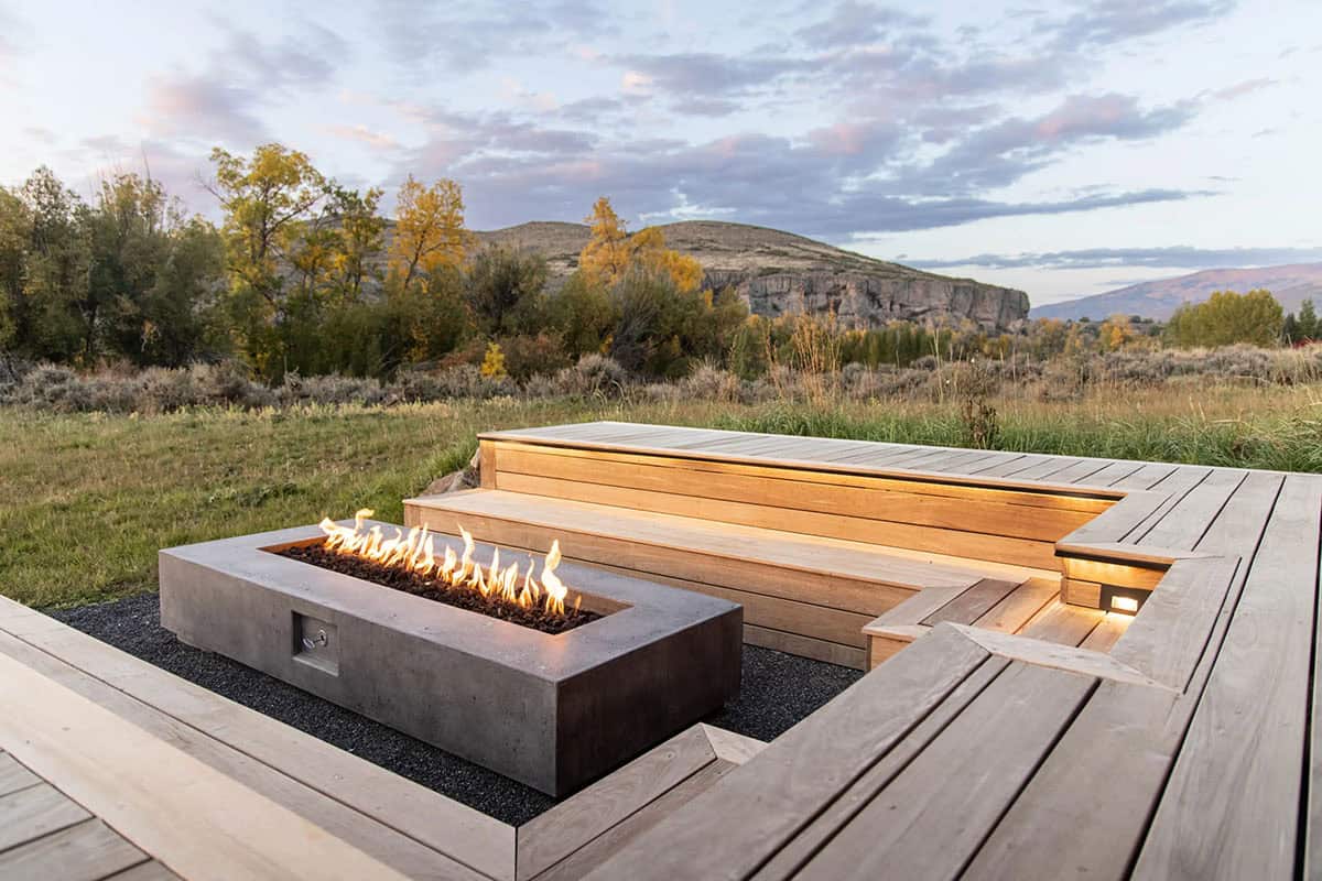 Concrete linear fire pit with cedar bench seating on a wood deck overlooking Utah mountain landscape at dusk