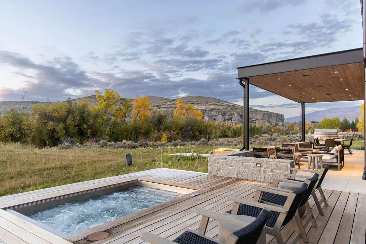 Wood deck with flush hot tub, lounge chairs, and autumn foliage and rock formations in the background