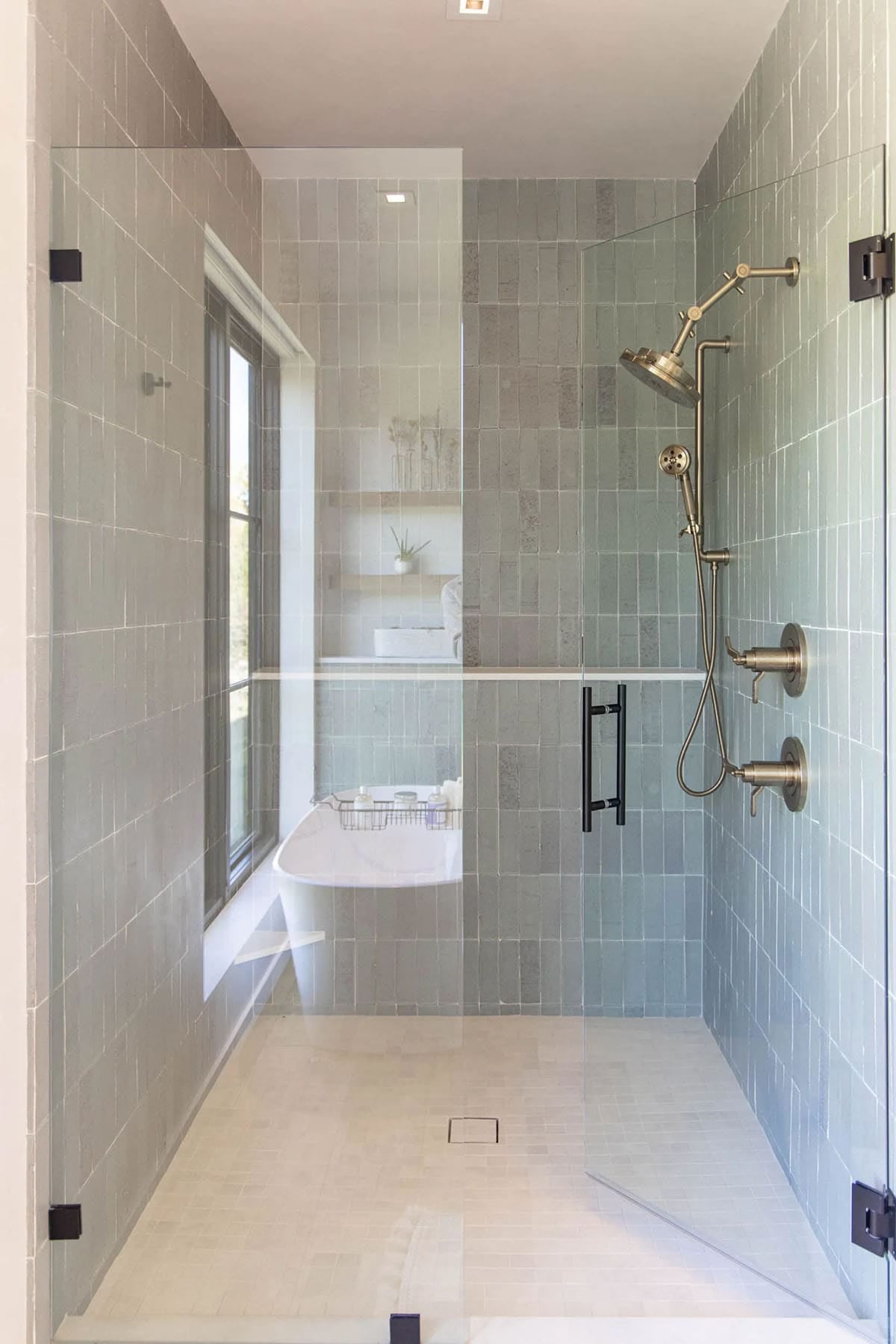 Walk-in shower with floor-to-ceiling sage zellige tile, glass door, and brushed brass fixtures