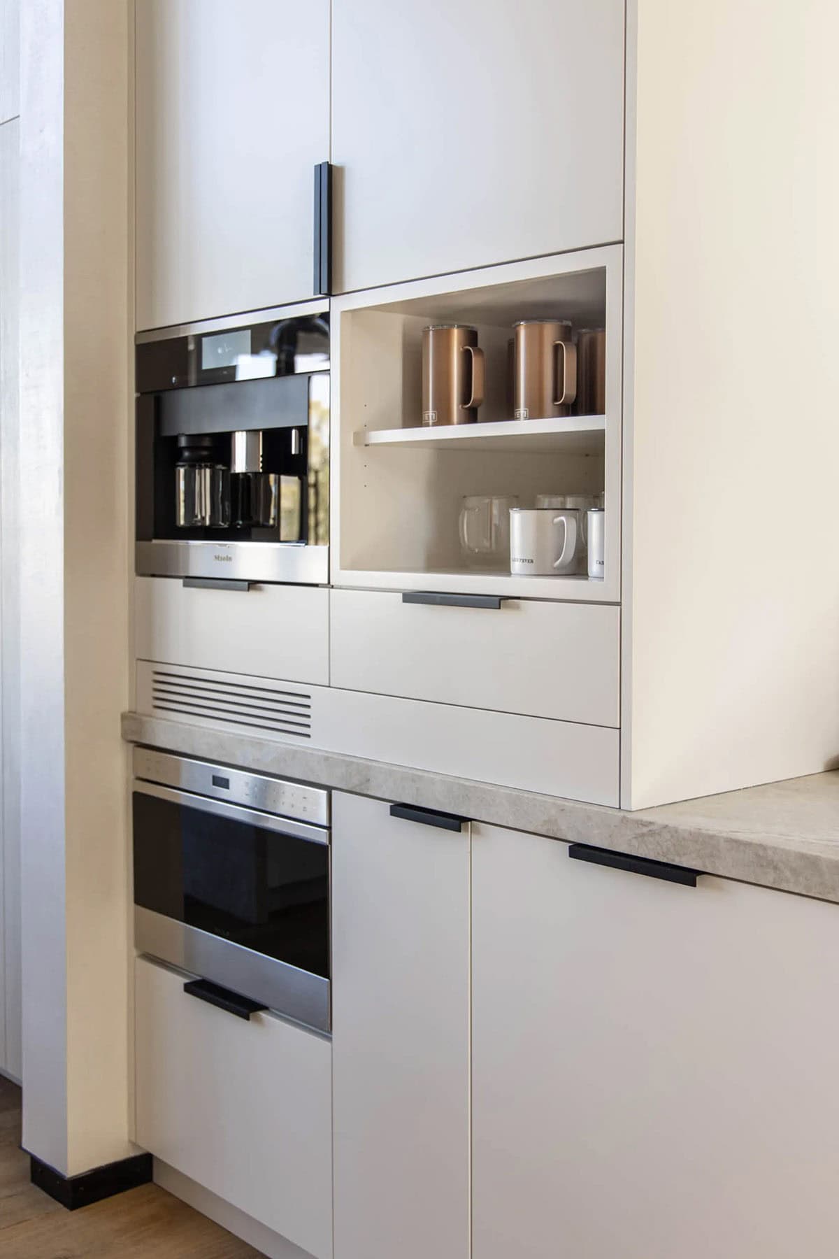 Kitchen appliance tower with built-in Miele coffee maker, wall oven, and open display shelf