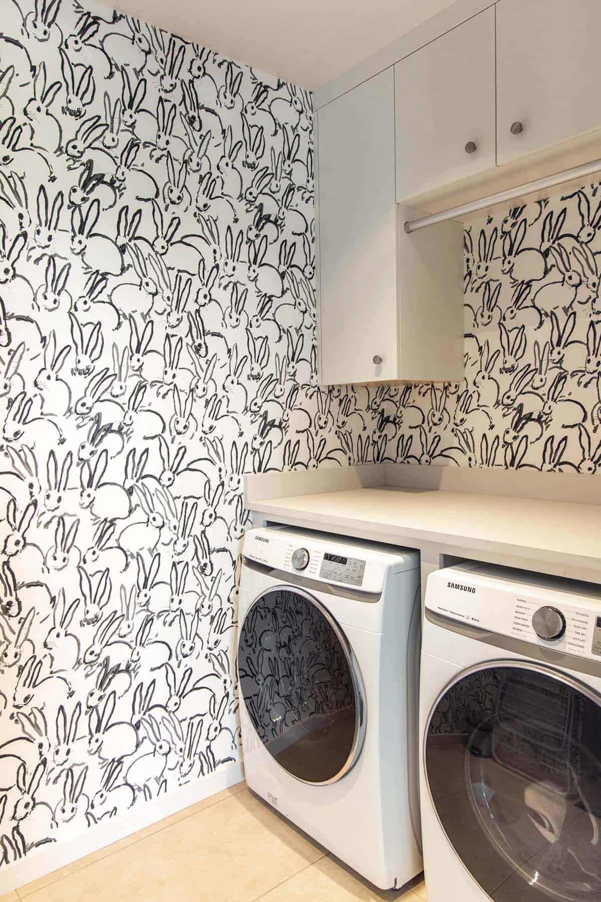 Laundry room with bold black-and-white bunny-print wallpaper and Samsung front-load washer and dryer