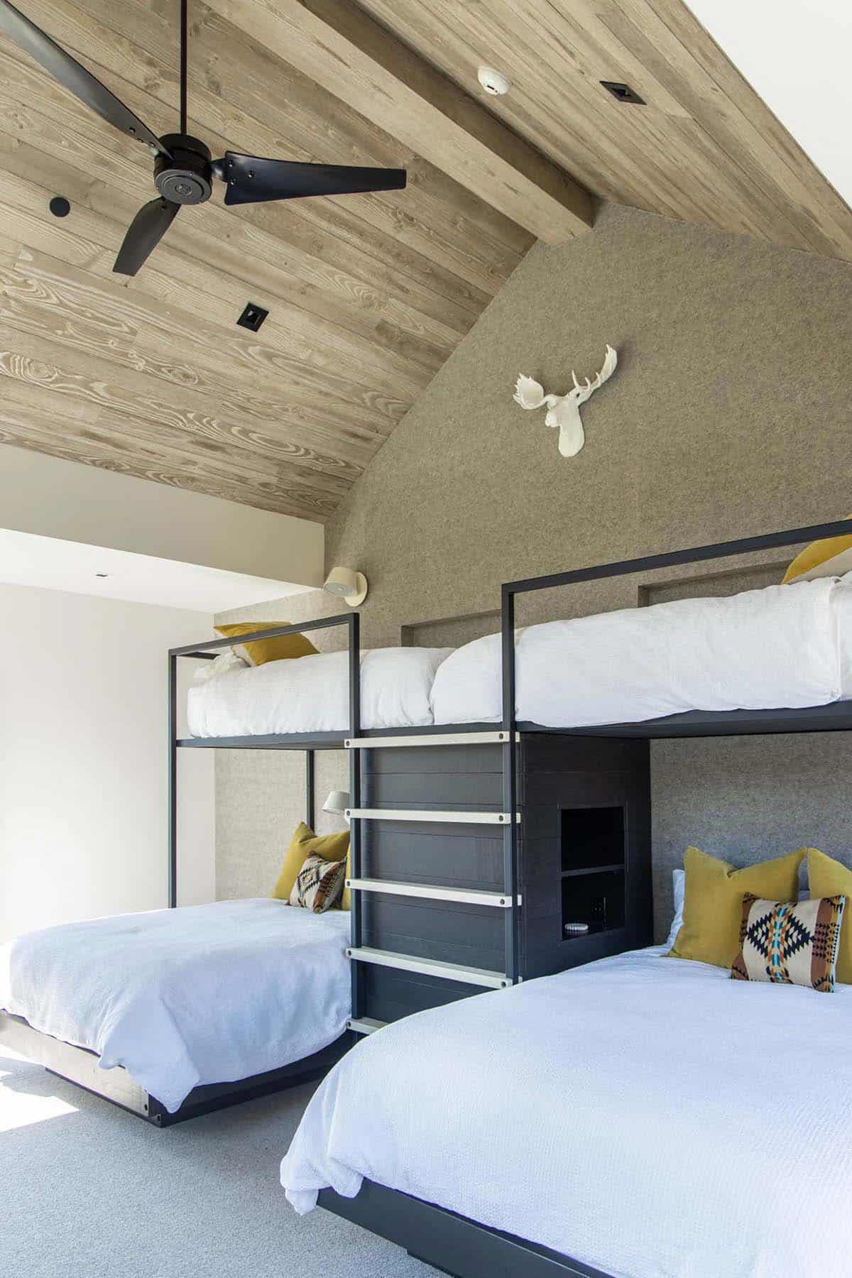 Bunk room with four custom black steel bunk beds, felt-upholstered headboards, vaulted wood ceiling, and moose trophy